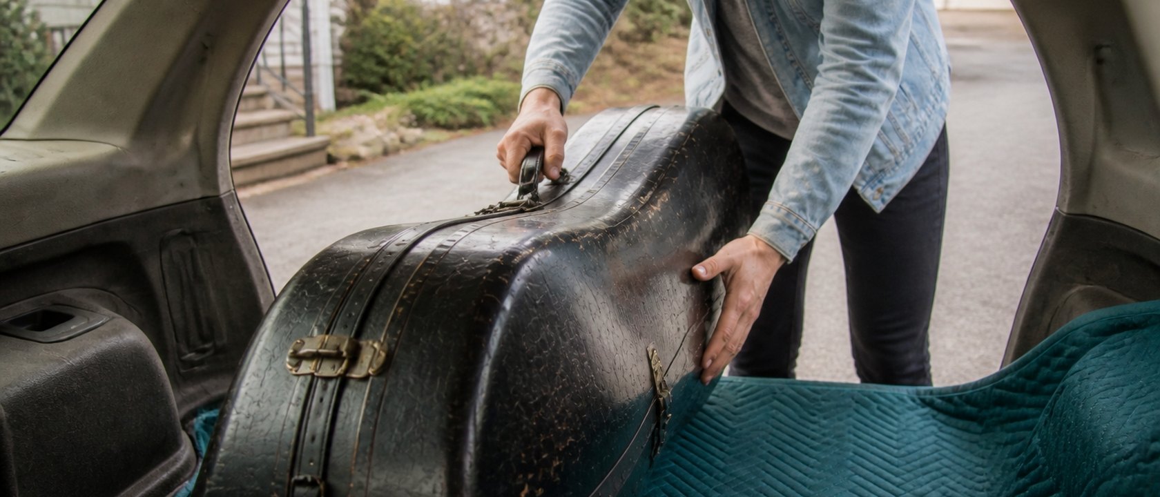 A student lifting an instrument case into a car.